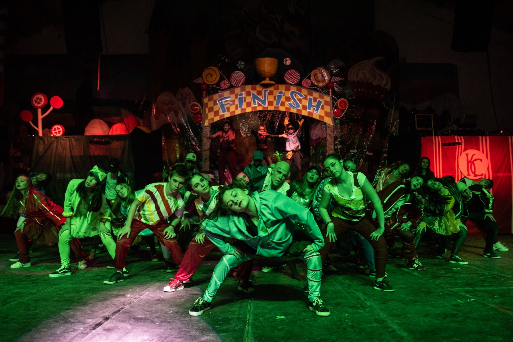 Grupo de bailarines iluminados en verde durante una presentación